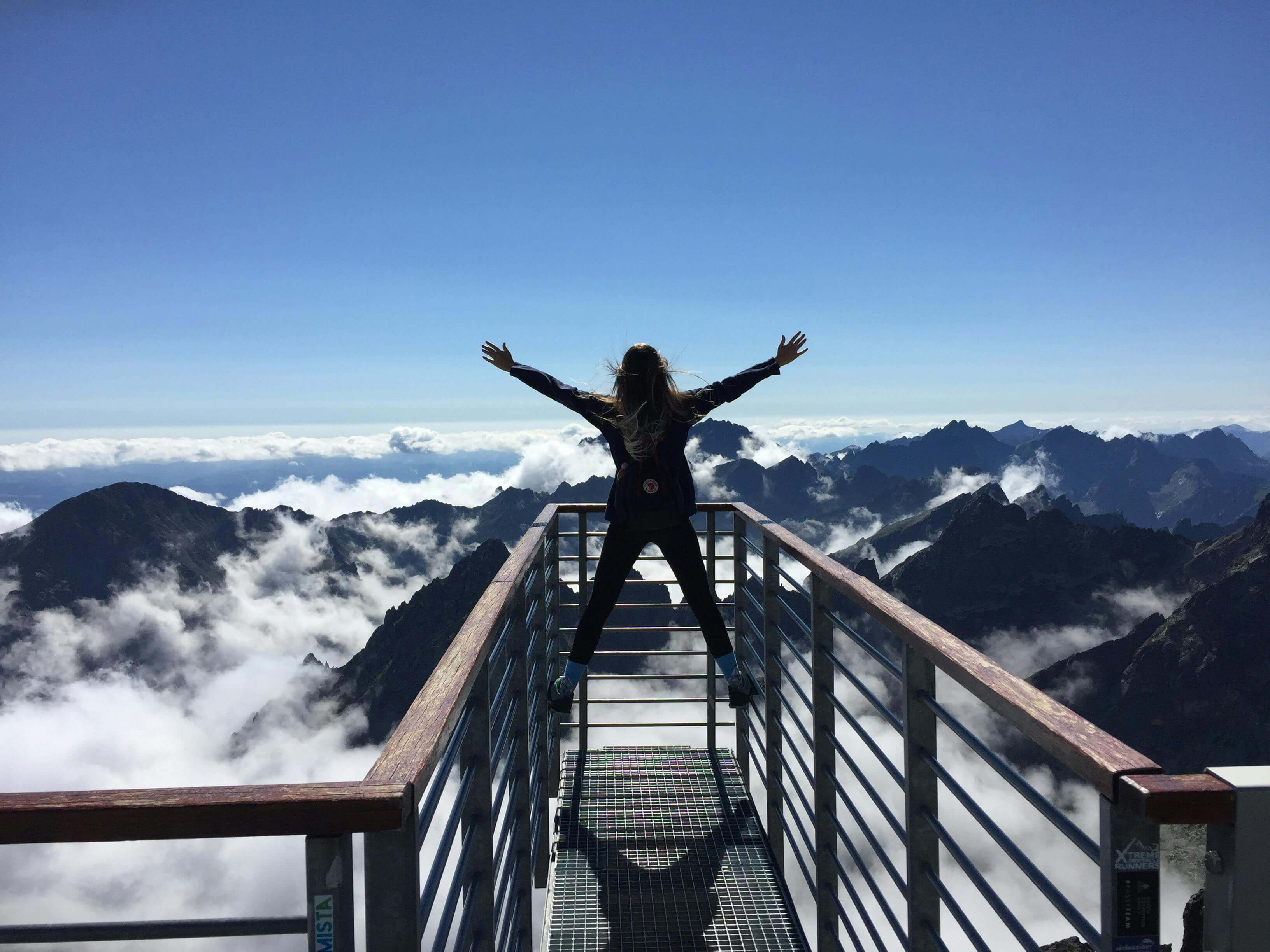 Ragazza a braccia aperte davanti alle montagne